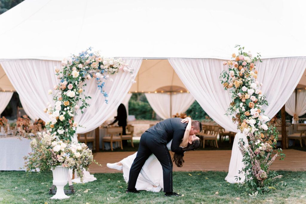 The couple kisses on wedding day in front of the tent